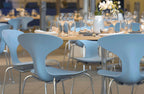 Blue chairs around a table with wine glasses in an indoor setting