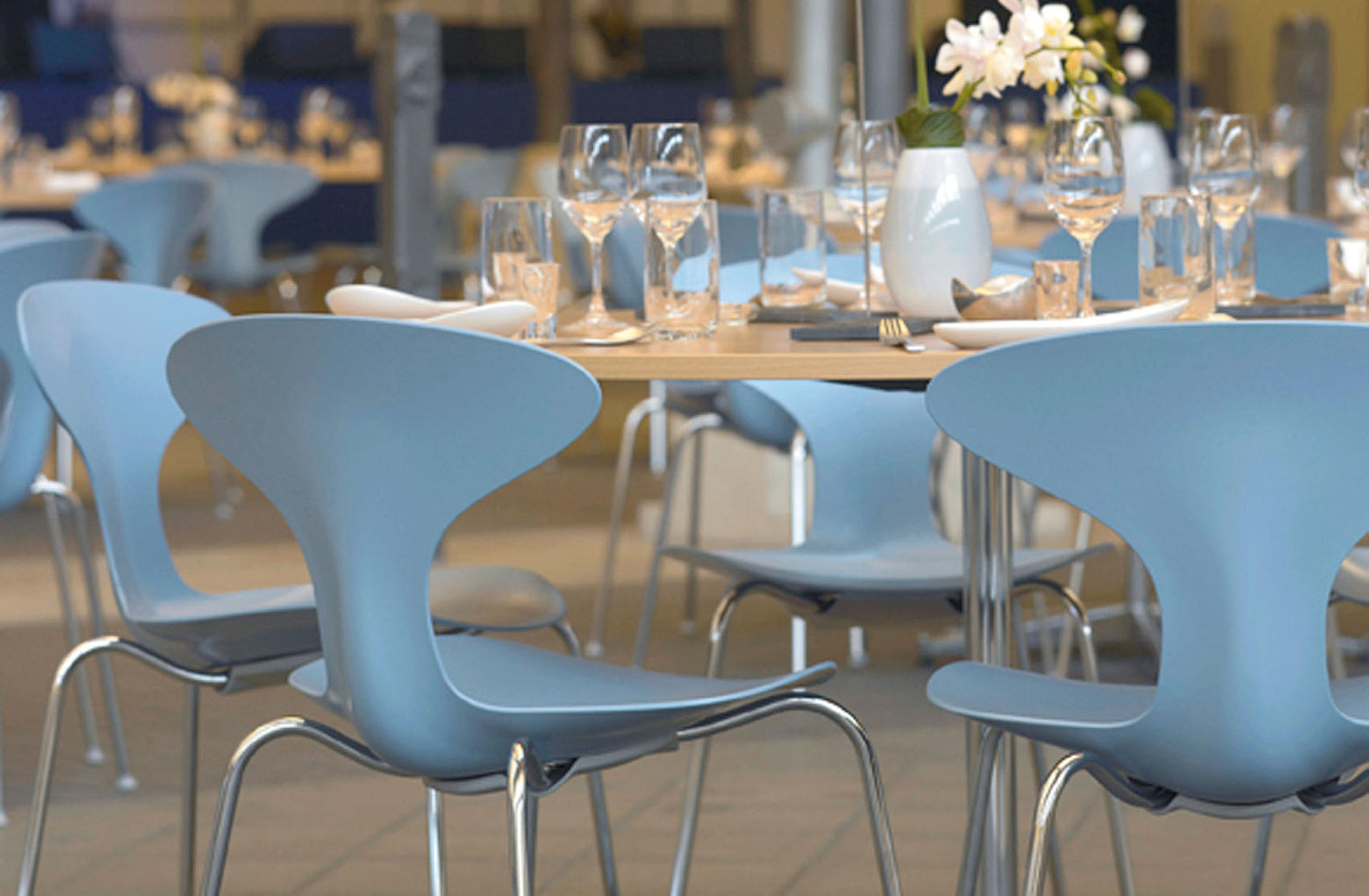 Blue chairs around a table with wine glasses in an indoor setting