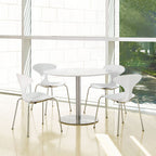 Modern white dining table with chairs in a bright room with large windows.