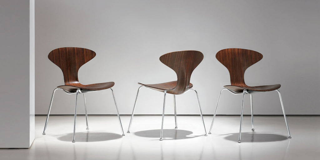 Three wooden chairs with metal legs on a white floor and wall