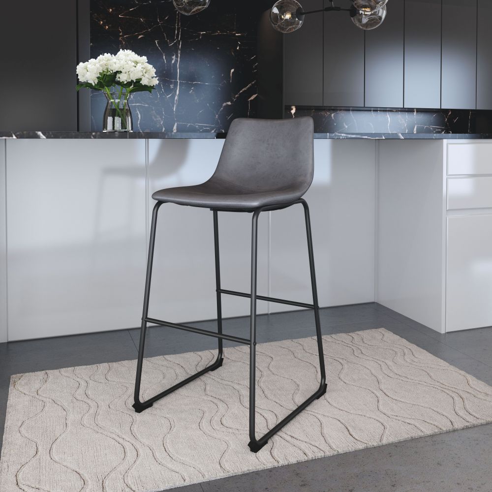 Gray bar stool in a modern kitchen setting with a black countertop and white cabinets.