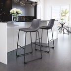 Two modern gray bar stools in a kitchen setting with a black countertop and white cabinets.
