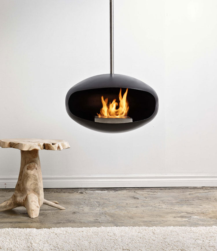 Modern hanging fireplace with flames inside, hanging from the ceiling with a white wall background.